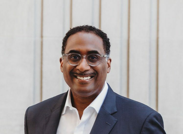black man smiling in suit and glasses